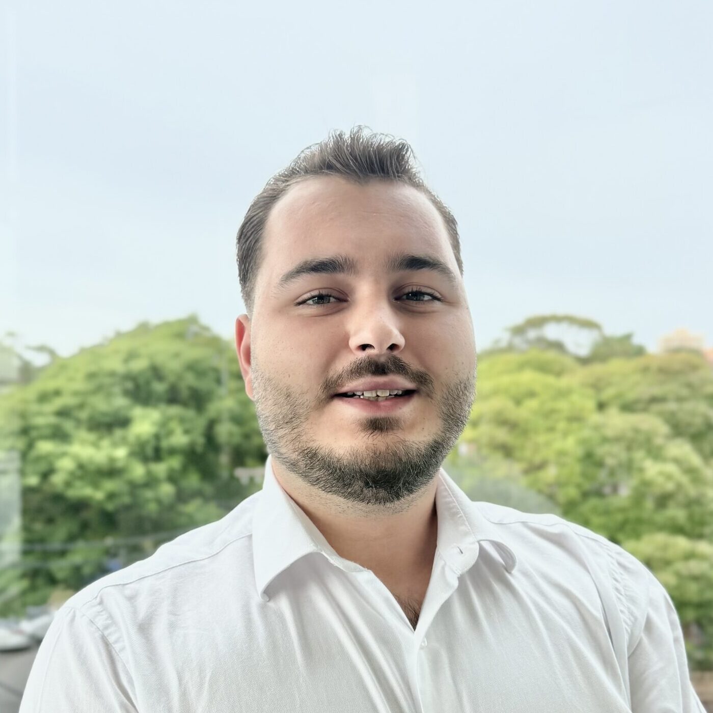 Jovan Radanovic Jovan Radanovic, Accountant, wearing a white collared shirt, smiling while standing in front of a leafy skyline
