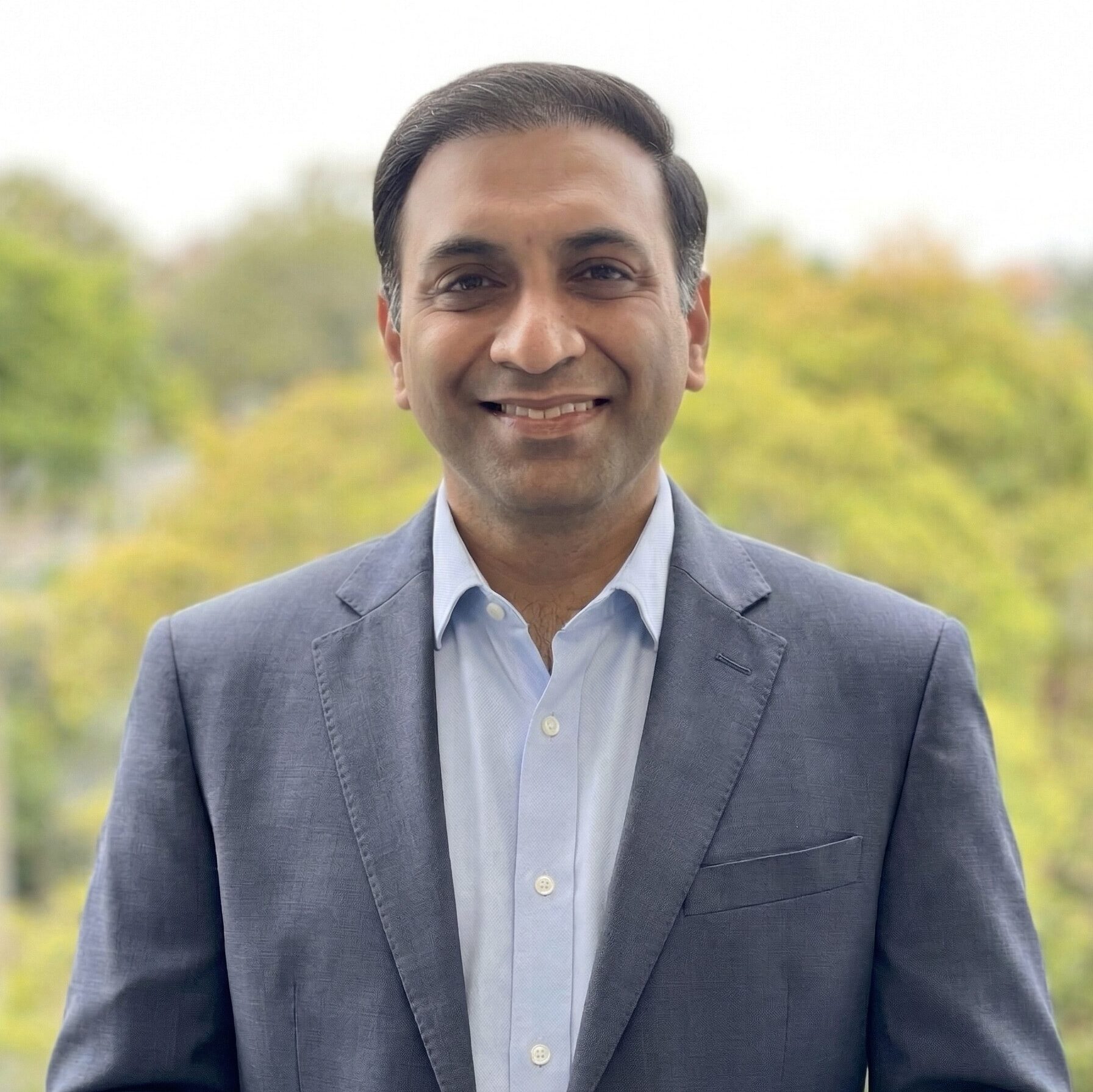 Shamir Gupta, Manager / Senior Accountant, wearing a patterned collared shirt, smiling while standing in front of a leafy skyline