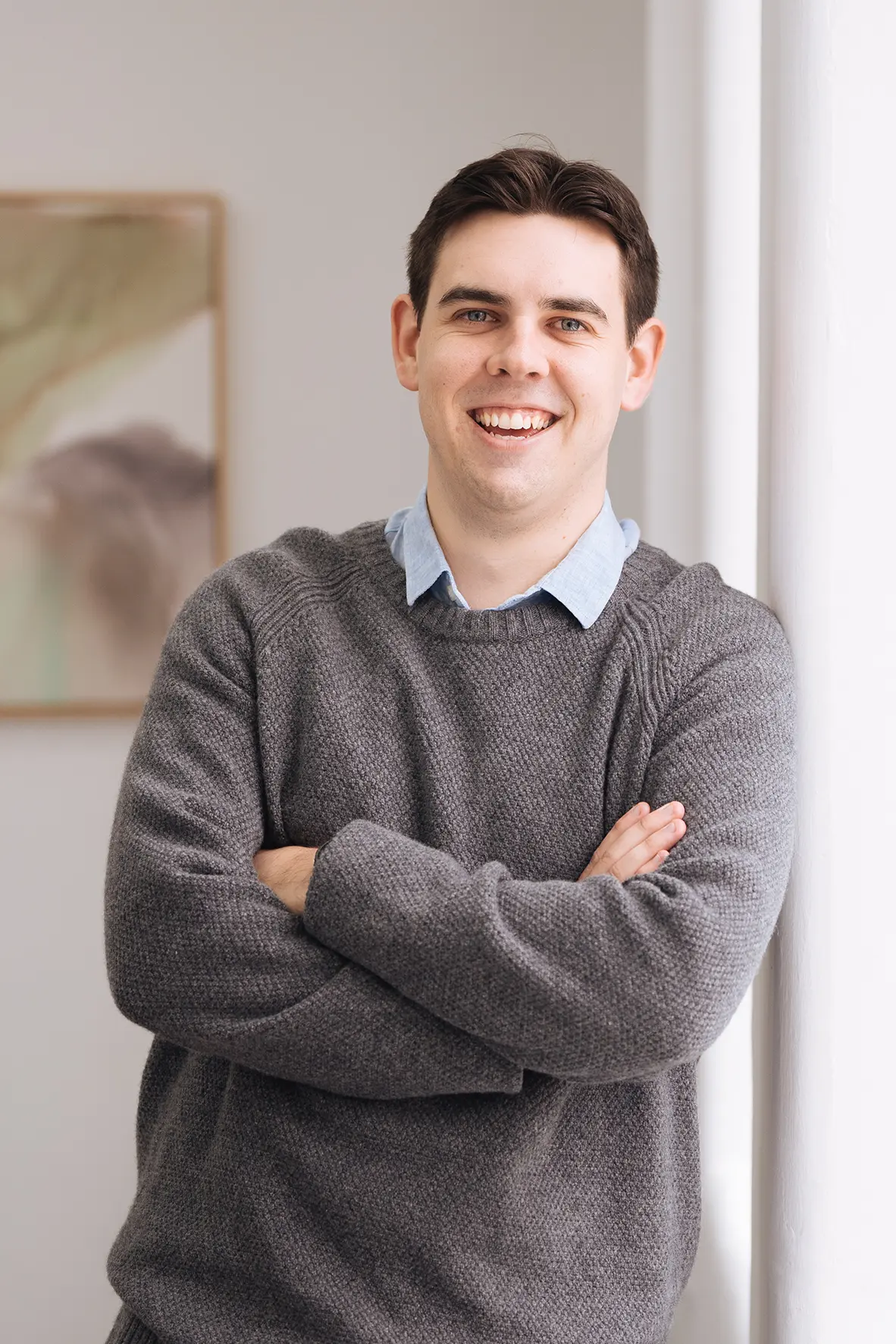 James_Gapps James Gapps, Accountant, smiling while leaning against a wall of a light-filled, elegant room