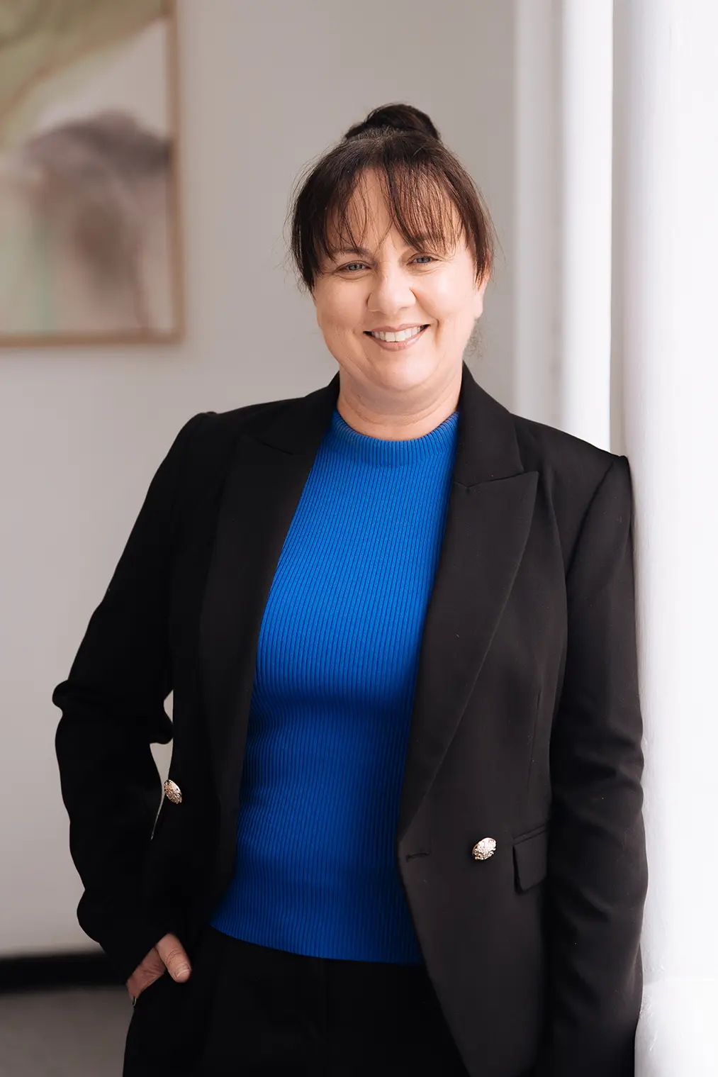Wendy_Byrne Wendy Byrne, Business Operations Manager, smiling while leaning against a wall of a light-filled, elegant room