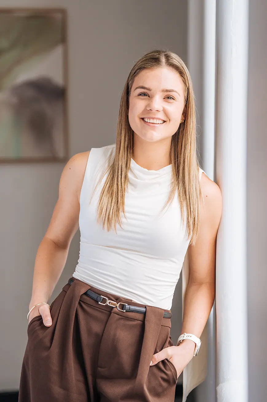 Brittany Mason, Senior Accountant and Client Manager, smiling while leaning against a wall of a light-filled, elegant room
