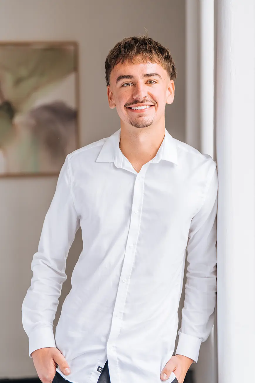 Ryan Mott, Accountant, smiling while leaning against a wall of a light-filled, elegant room